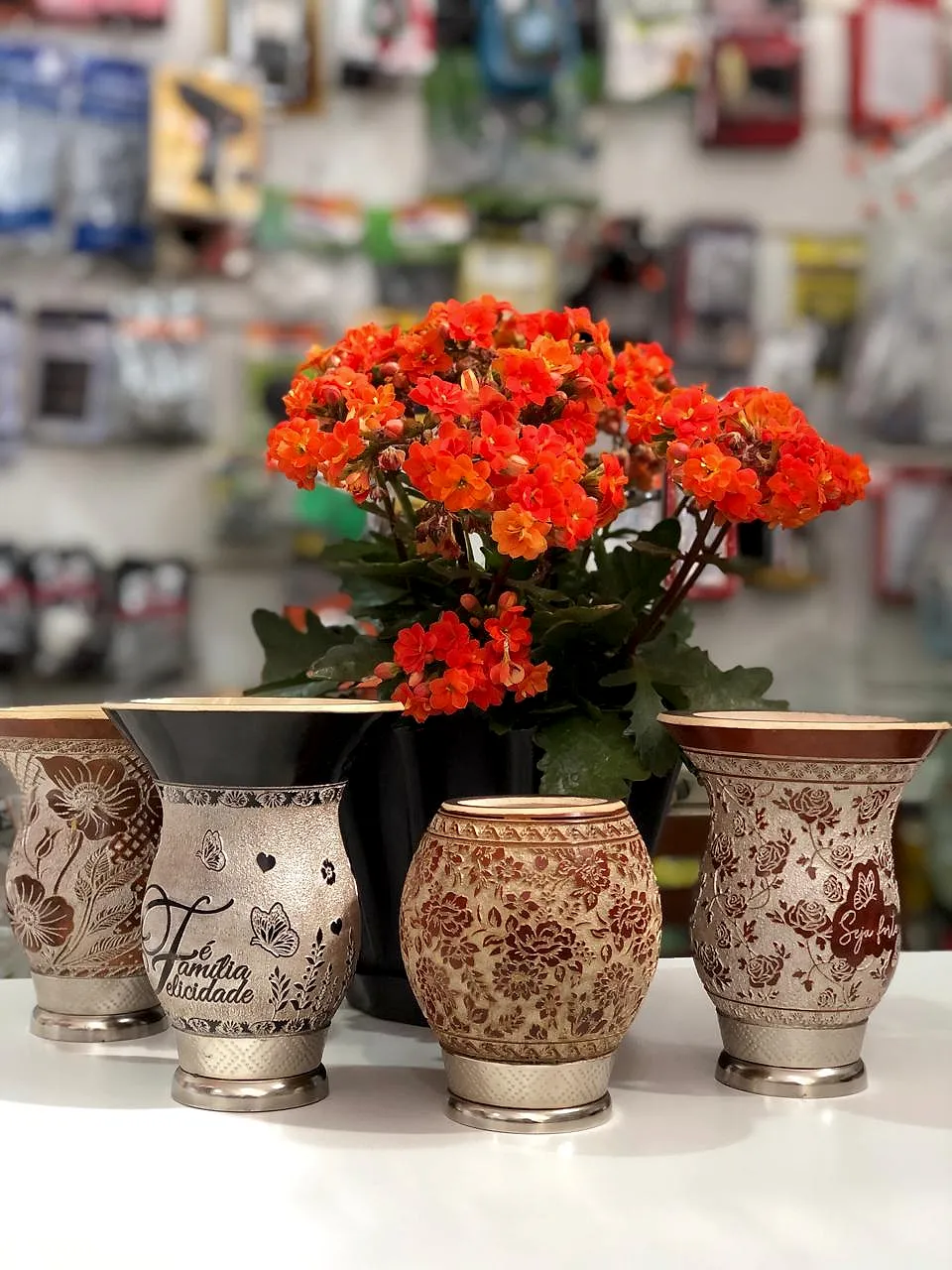 Cuias de chimarrão decoradas e uma flor laranja sobre o balcão